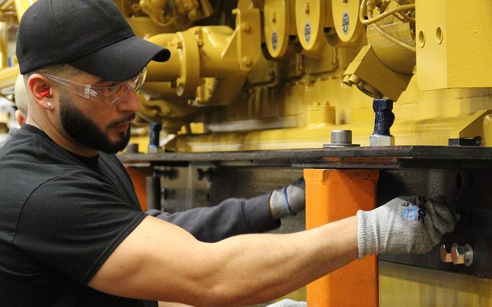 A Caterpillar employee working beside a large engine in Lafayette
