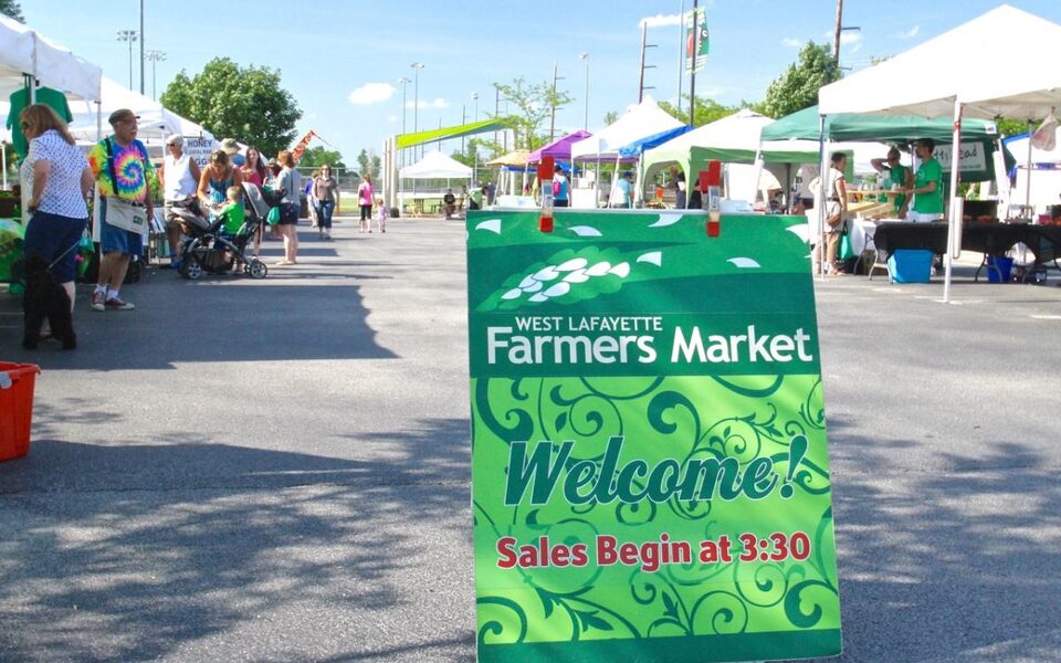 Welcome sign and vendor tents at the West Lafayette Farmers Market